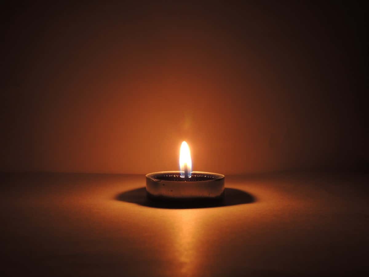 A single tea light candle burning in a dark room